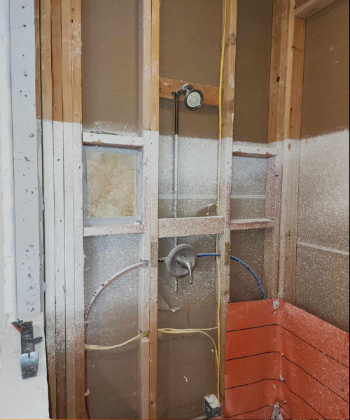 An unfinished bathroom with a shower and plumbing