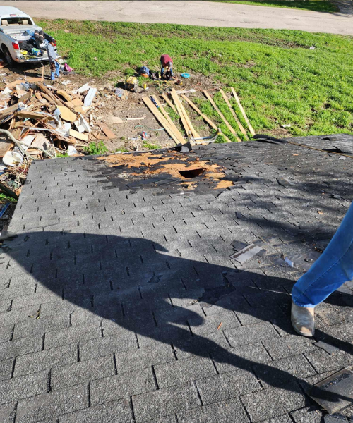 A person standing on top of a roof next to a pile of debris