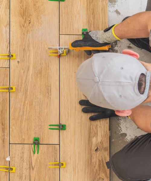 A pair of hands holding a hat over a wooden floor