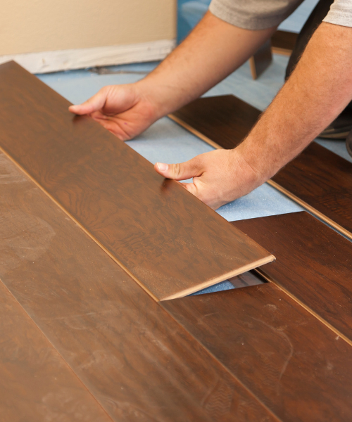 A person is laying laminate on the floor