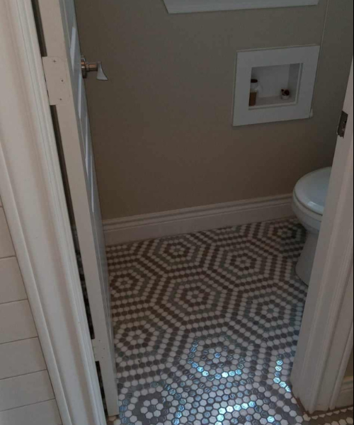 A bathroom with a toilet and a tiled floor