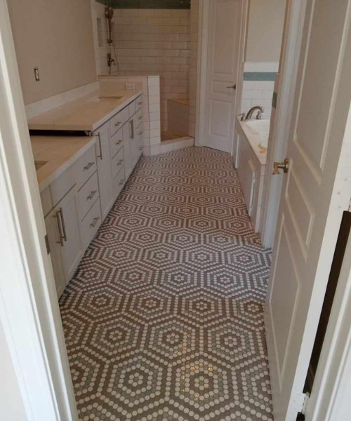 A bathroom with a tiled floor and white cabinets